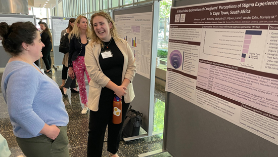 A researcher discussing her research poster behind her.