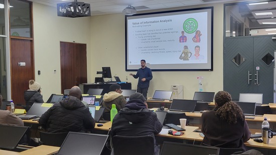 Ciaran Kohli-Lynch teaching a course in front of a classroom of students